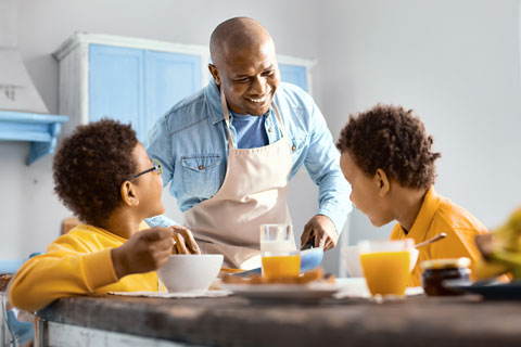 Father and sons eating at kitchen table