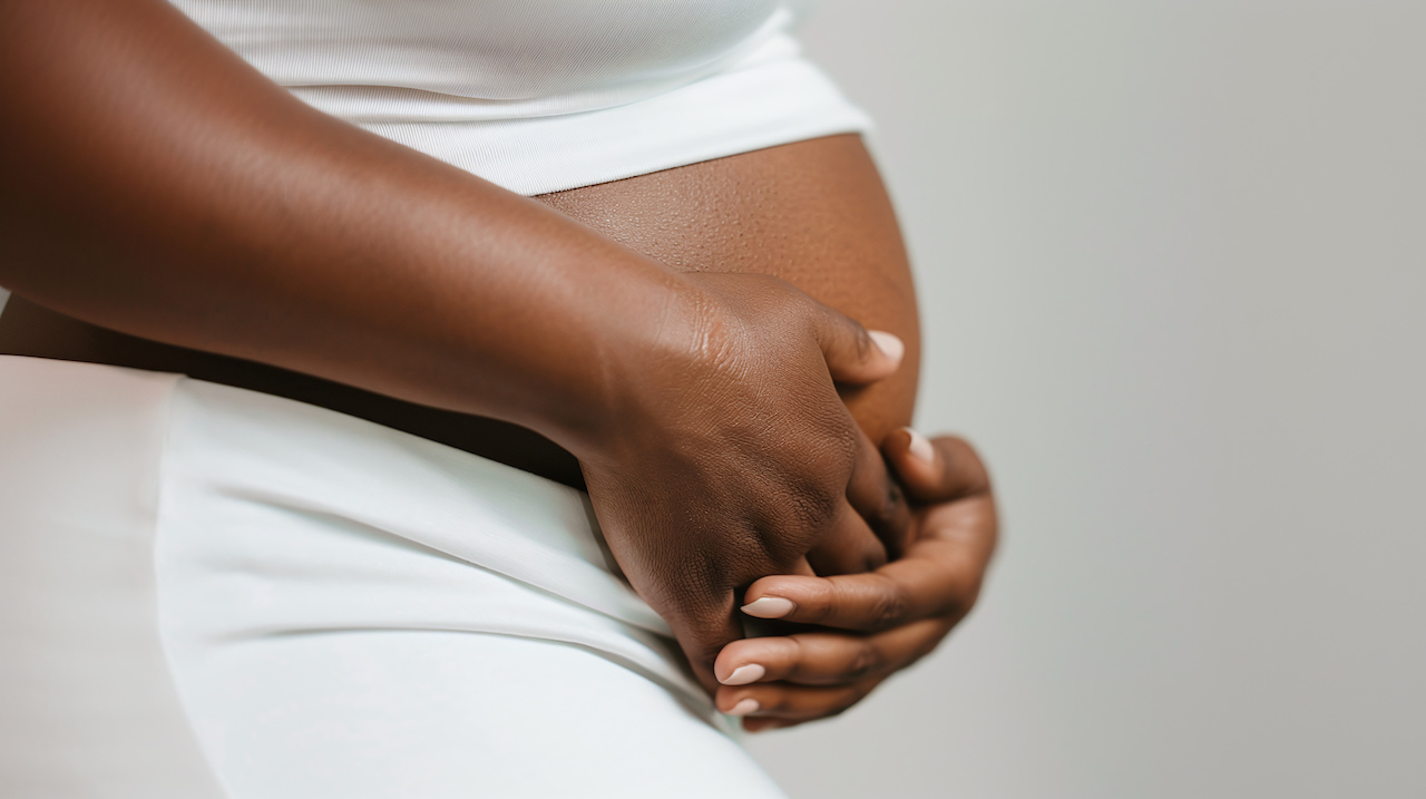 close-up of a black woman's hands on pregnant belly jpeg