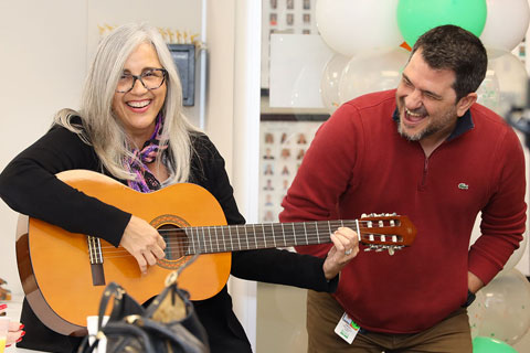 Staff playing the guitar and smiling